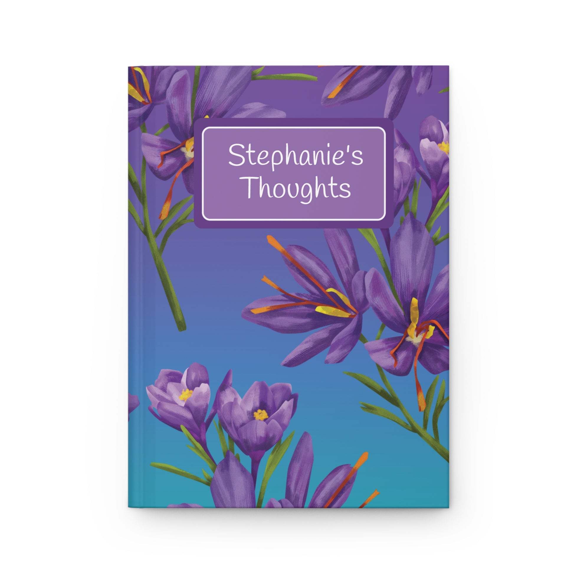A hardcover notebook with a purple and blue floral cover featuring purple flowers and green stems. A white rounded rectangle label on the cover reads 'Stephanie's Thoughts'.
