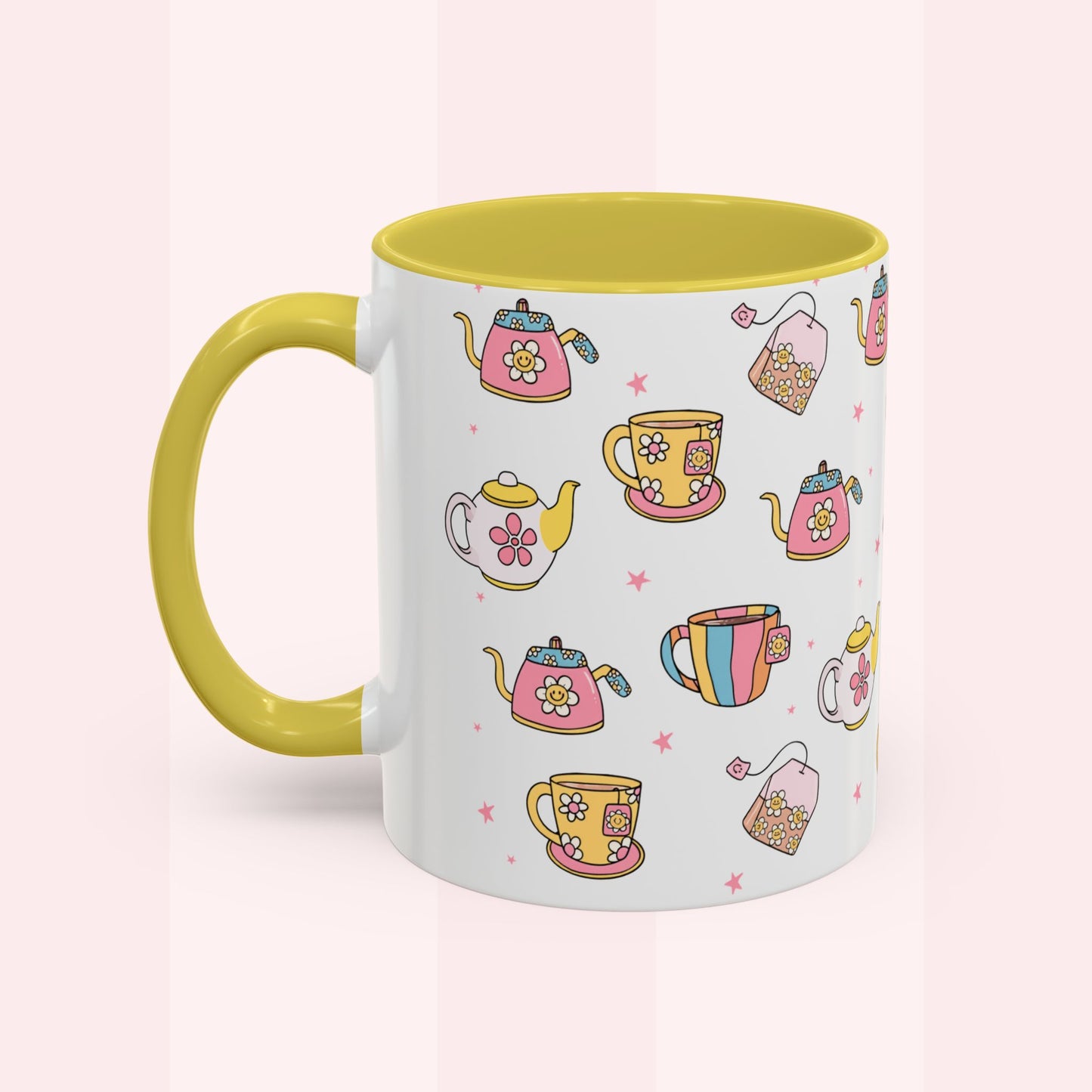 A white ceramic mug with a bright yellow handle and interior, decorated with a colorful pattern of teapots, teacups, and tea bags on a soft pink background.