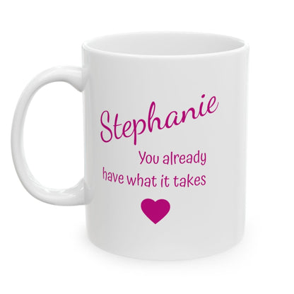 A white ceramic mug with pink printed text reading 'Stephanie You already have what it takes' and a small pink heart, shown on a white background with a light pink border.