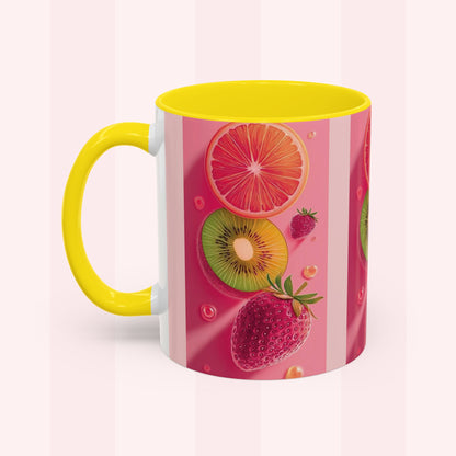 A ceramic mug with a bright yellow handle and interior, decorated with a pink and white striped design featuring illustrations of sliced grapefruit, kiwi, strawberry, and raspberry.