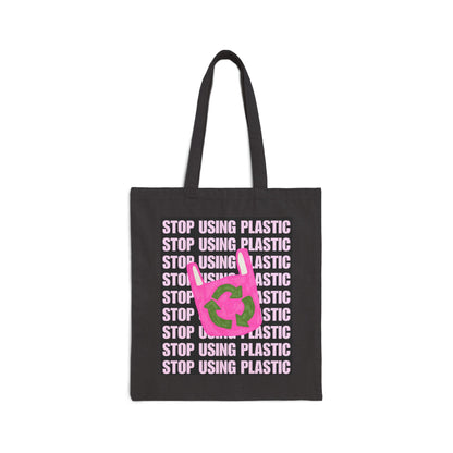 A black canvas tote bag with long black handles, featuring a graphic print of the word 'STOP' in light pink text repeated vertically, overlaid with a bright pink recycling symbol with green arrows.